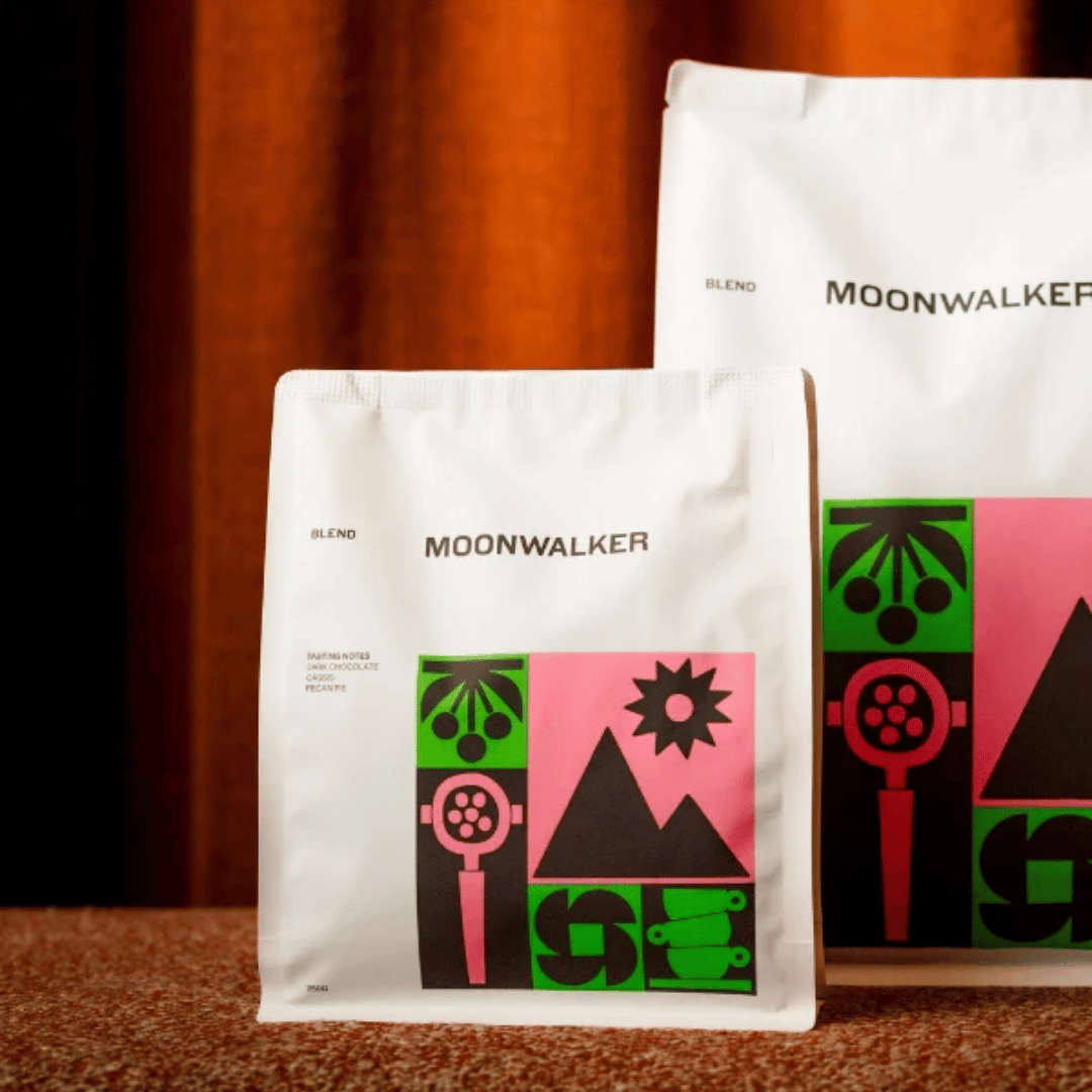 Two Moonwalker coffee bags with colorful designs on a wooden surface.