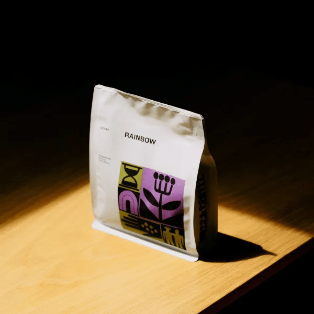 White coffee bag with colorful design and 'Rainbow' text on a wooden surface