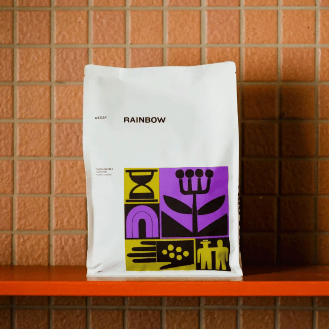 White coffee bag with colorful graphics and 'Rainbow' branding on a tiled shelf.